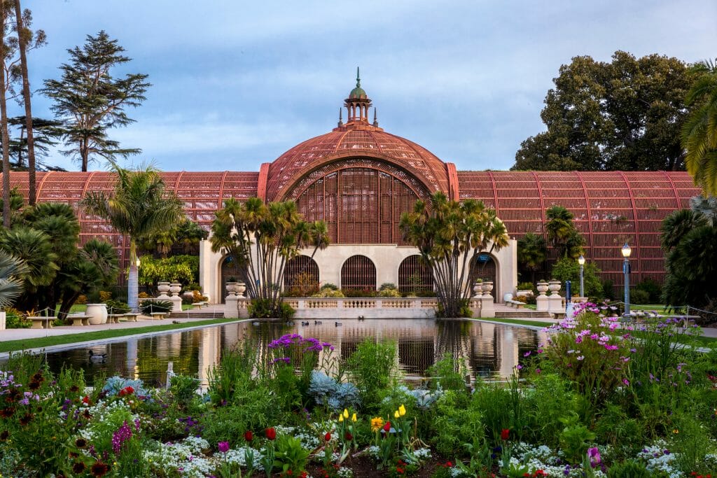 Arboretum expanding over the frame with foliage all around and a pond in front of it in Balboa Park, San Diego