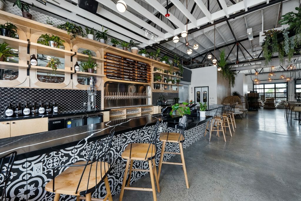 Modern Bar in restaurant. Plants line the walls of the bar, beer is tapped up to the levers and the seats are empty and awaiting guests