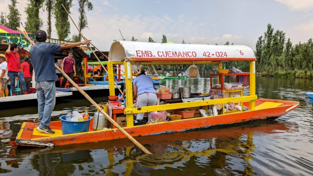 Colorful wooden boats on Heron sitting by the banks of the canals at Xochimilco