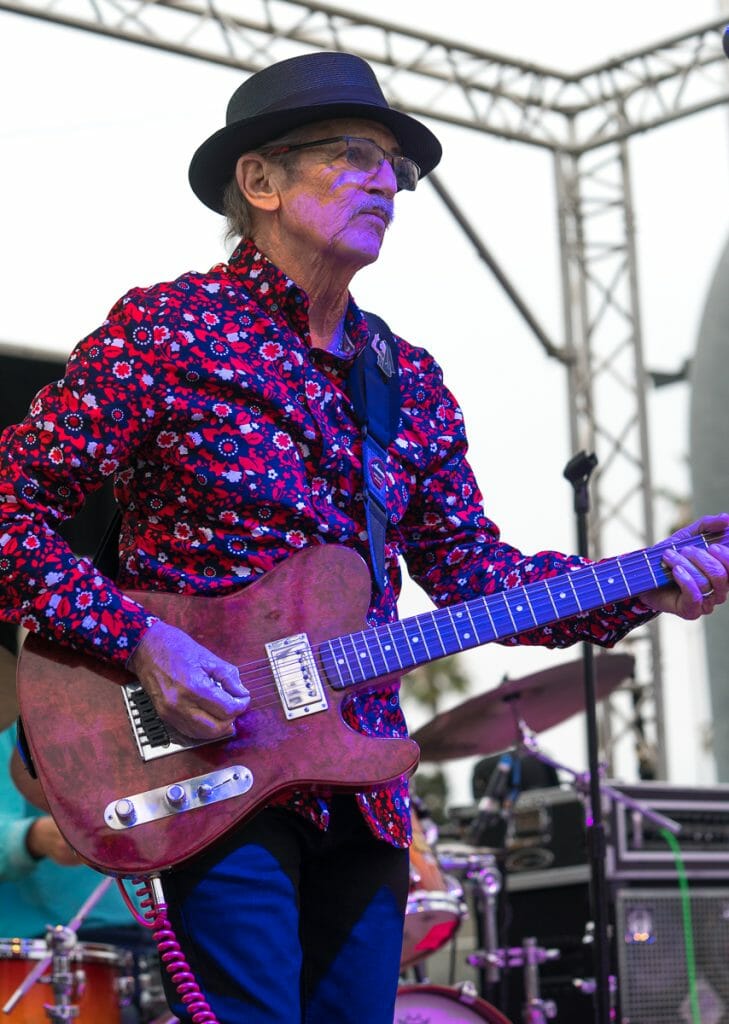 Man with hat playing guitar on a stage