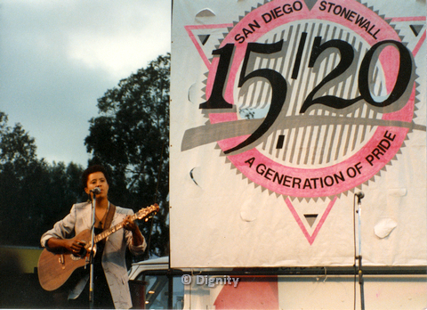 1989 deidre mccalla playing guitar in front of large design that says 1520 san diego stonewall a generation of pride