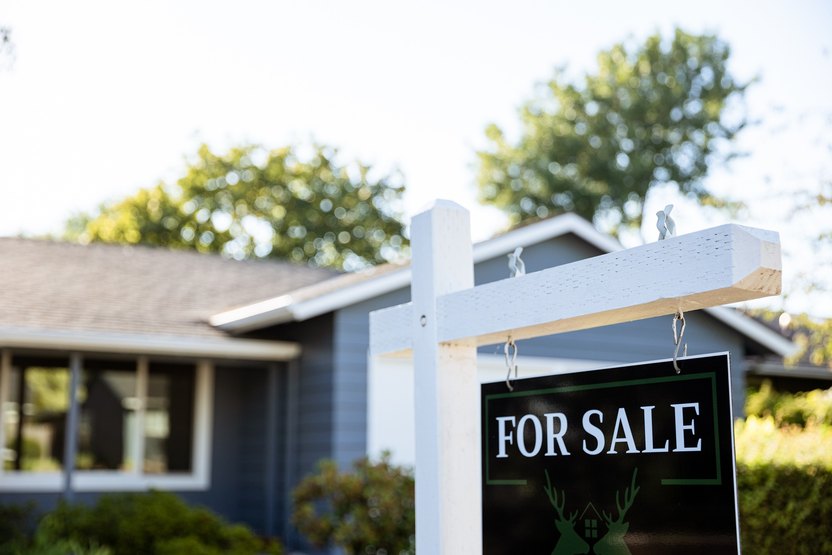 Image of a real estate for sale sign posted in front of a residential home