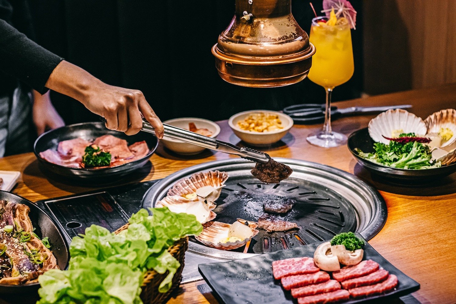 People grilling meat at new San Diego Korean restaurant Sura Korean BBQ