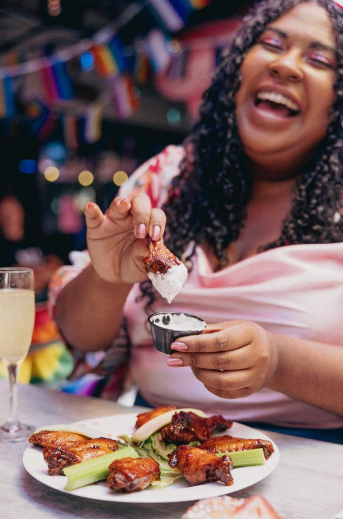 Woman eating wings at gossip grill