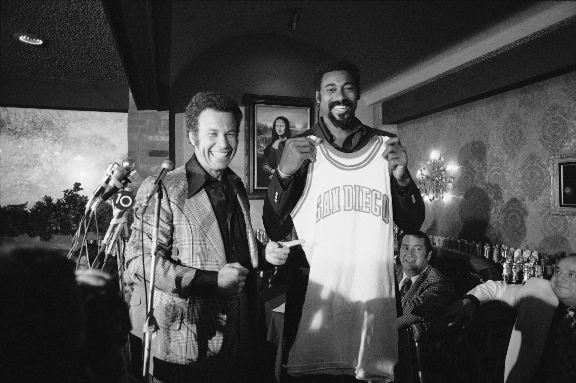 Leonard Bloom, at left, owner of the San Diego Conquistadors with Wilt Chamberlain, the veteran Los Angeles Lakers center, holding up his new shirt at a news conference, Wednesday, Sept. 26, 1973 in Chula Vista. Chamberlain was joining the American Basketball Association team as player-coach. (AP Photo)