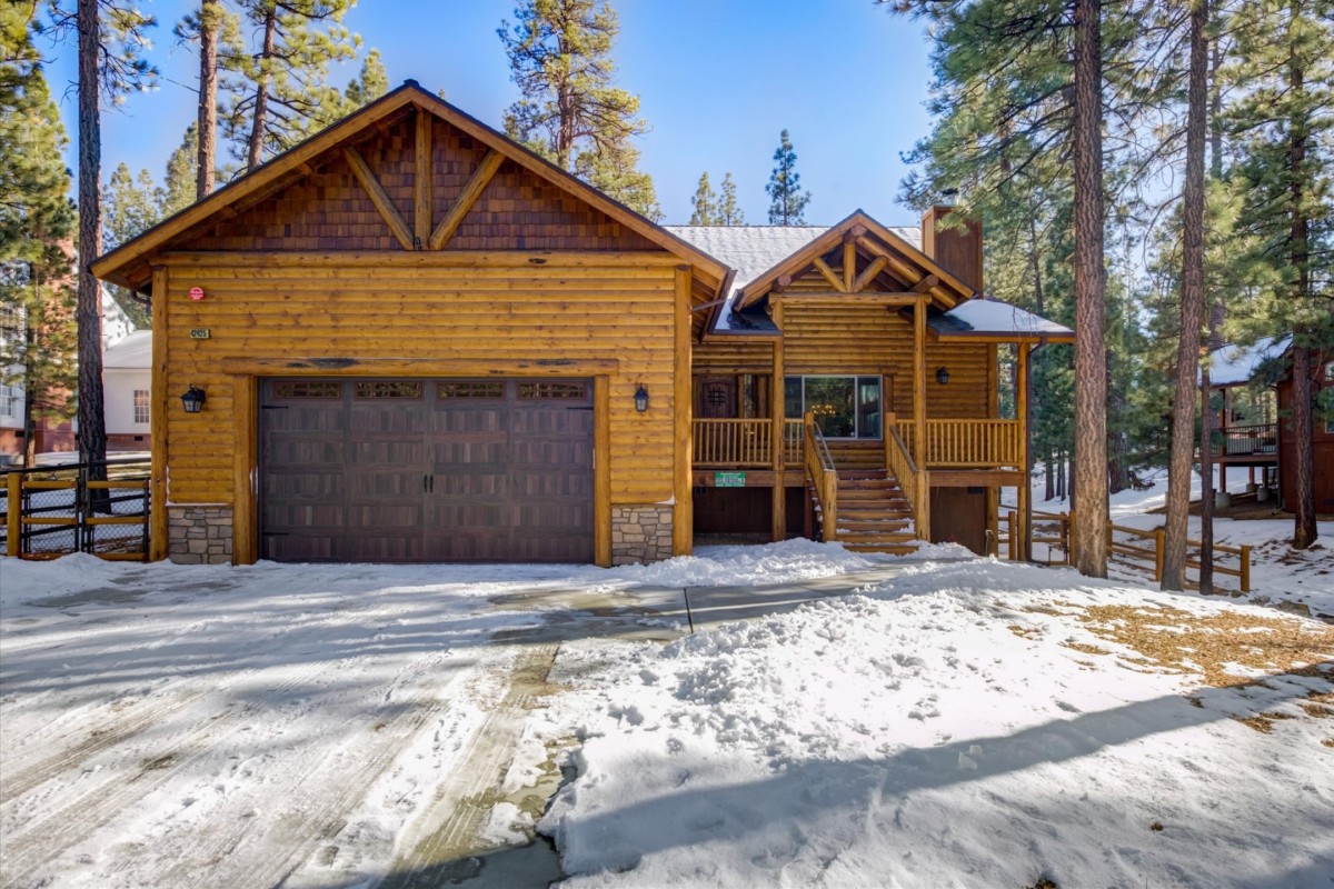 home in a wooded, snowy area with steps leading up to the house