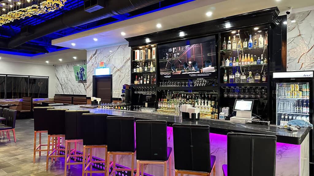 interior of a restaurant with a bar lit up in purple lights 