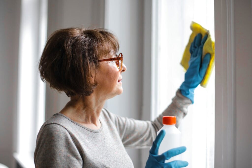 Woman cleaning windows while holding a bottle