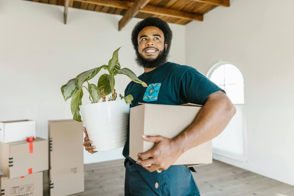 Man holding a box and a plant