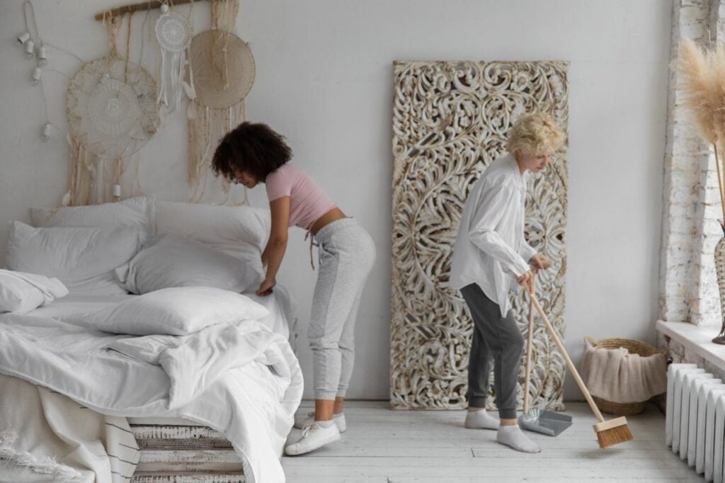 two women cleaning and tidying up a white room