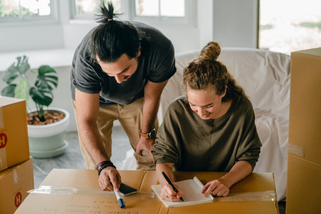 A couple writing down notes on a big cardboard box