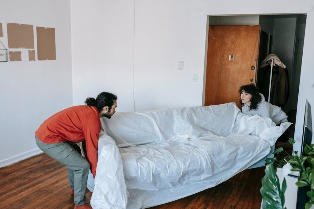 Man and woman moving a couch covered with paper