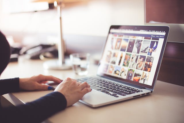 A person scrolling social media on a laptop.