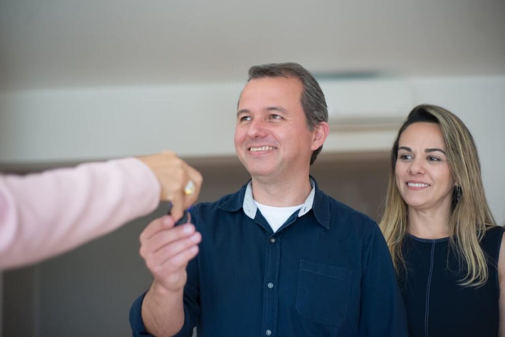 A realtor handing a key to a couple.