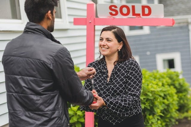 a man handing the key to the woman while shaking their hands