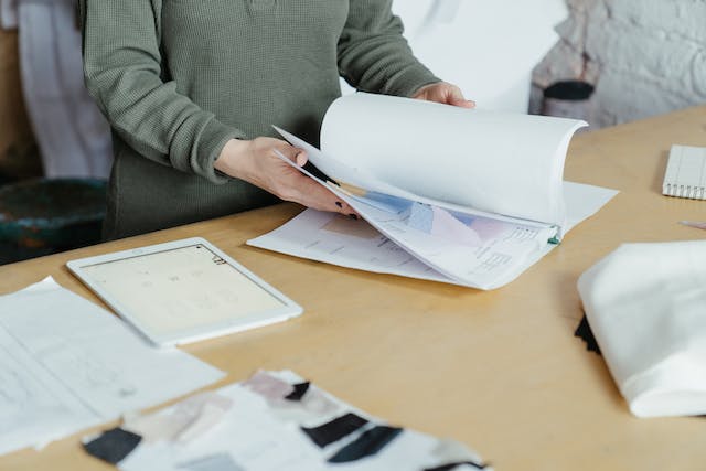 Person in gray sweater holding white printer paper