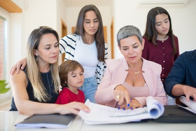 Large family sitting at a desk, looking at blueprints, and researching selling in a slow market