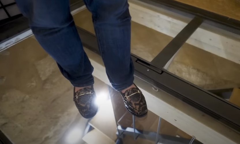 Part of the bedroom's floor is transparent, and you can see down into the dry sauna room below.