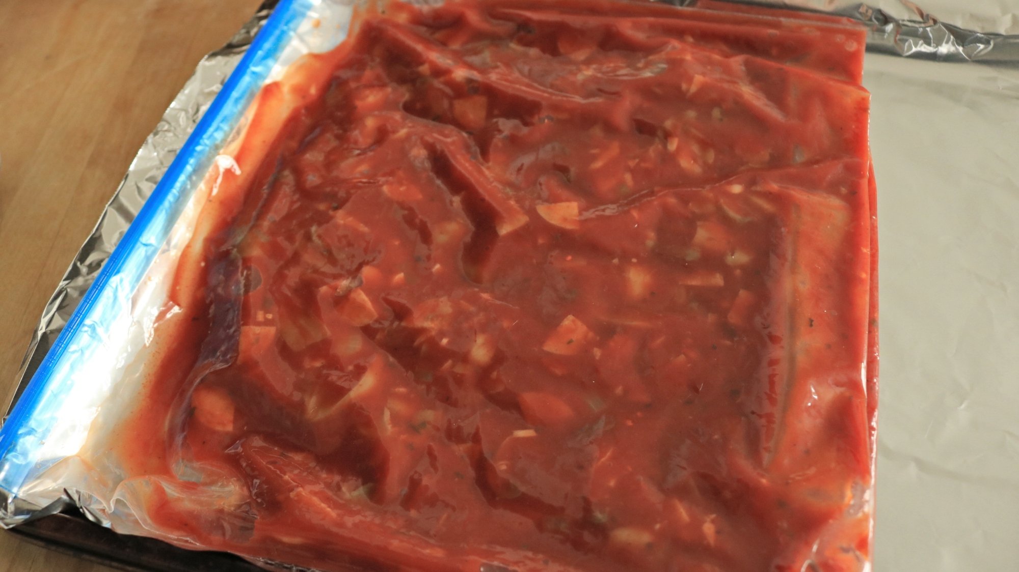 A bag of tomato sauce on a metal sheet pan.
