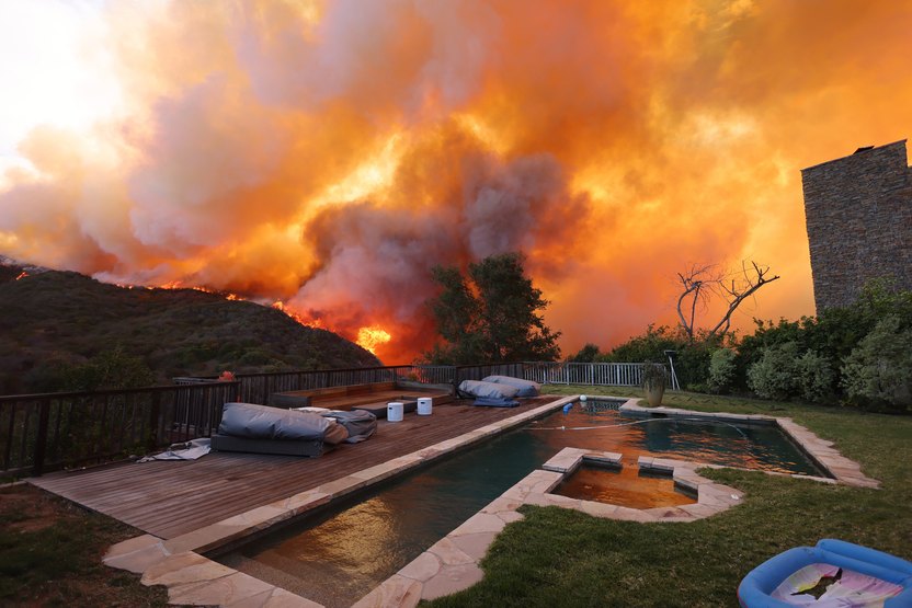 A fast-moving brushfire in a Los Angeles suburb burned buildings and sparked evacuations Tuesday as "life threatening" winds whipped the region