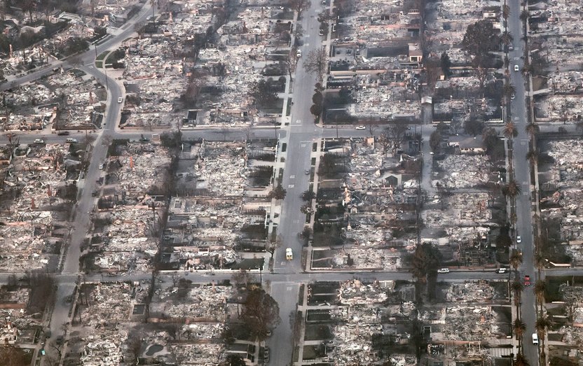 PACIFIC PALISADES, CALIFORNIA - JANUARY 09: An aerial view of an emergency vehicle (C) driving past destroyed homes as the Palisades Fire continues to burn on January 09, 2025 in Pacific Palisades, California. Multiple wildfires fueled by intense Santa Ana Winds are burning across Los Angeles County. At least five people have been killed, and over 25,000 acres have burned. Over 2,000 structures have also burned and almost 180,000 people are under orders to evacuate. (Photo by Mario Tama/Getty Images)