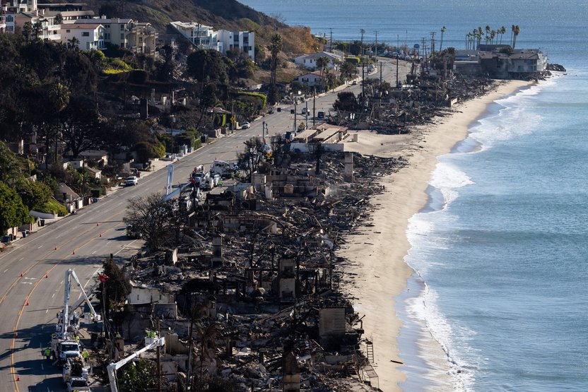 Vehicles run on the Palisades section of Pacific Coast Highway along scorched structures and trees by wildfires.