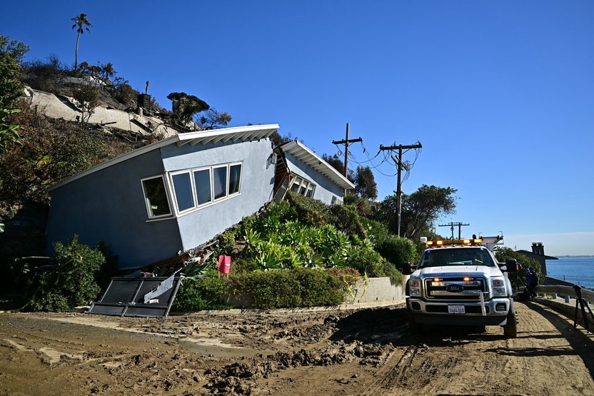 A utility truck is parked in front of a house previously unscathed by the Palisades fire and now split in half by a landslide in the Pacific Palisades neighborhood of Los Angeles, California