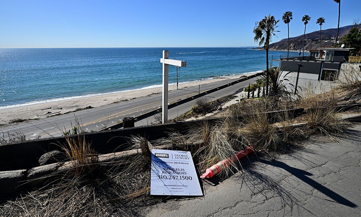 A real estate sign is seen on the ground near beachfront properties ravaged by the Palisades Fire, in the Pacific Palisades neighborhood of Los Angeles