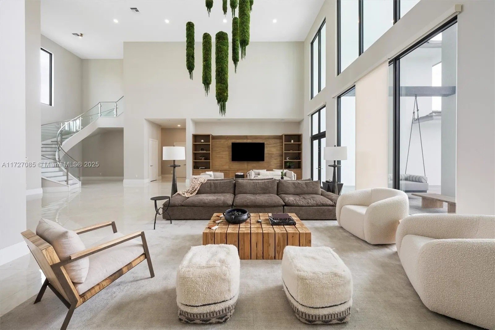 large white room with glass windows and a moss chandelier