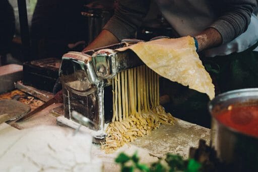 Man rolling out fresh spaghetti with a cluttered work space