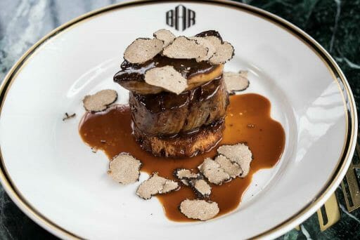 A filet mignon rested on a bed of sauce with truffles shaved over the tops