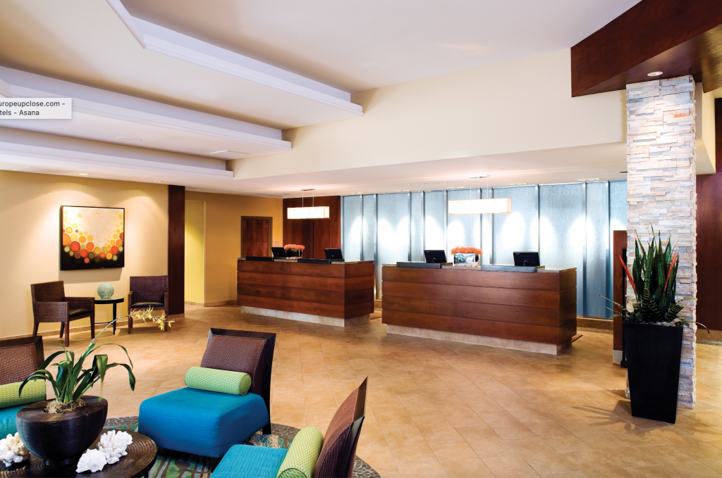 Two dark brown desks in the middle of the lobby with bright lights