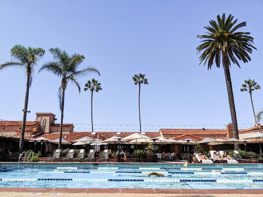 View of pool in the front with pool chairs in the background at the La Jolla Beach & Tennis Club