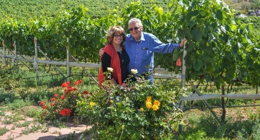 Denise and Peter Clarke, Owners of Altipiano winery posing in front of their vineyards