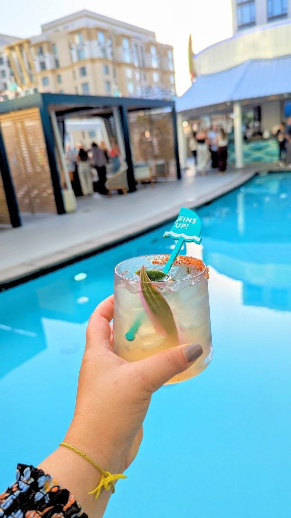 hand holding a cocktail next to a rooftop pool at 5 o'clock somewhere bar at Margaritaville Hotel San Diego