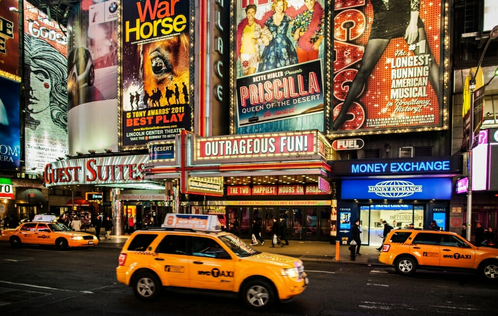 Broadway New York City with Advertisement for plays and yellow cabs in the street in front