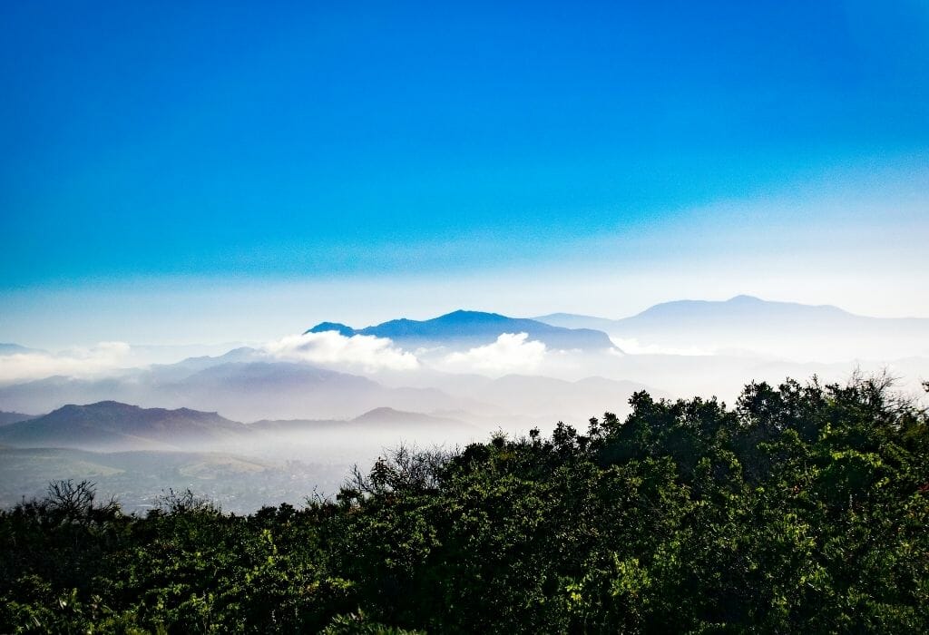 misty mountains in the background with blue sky above and green hills in the foreground - laguna mountains