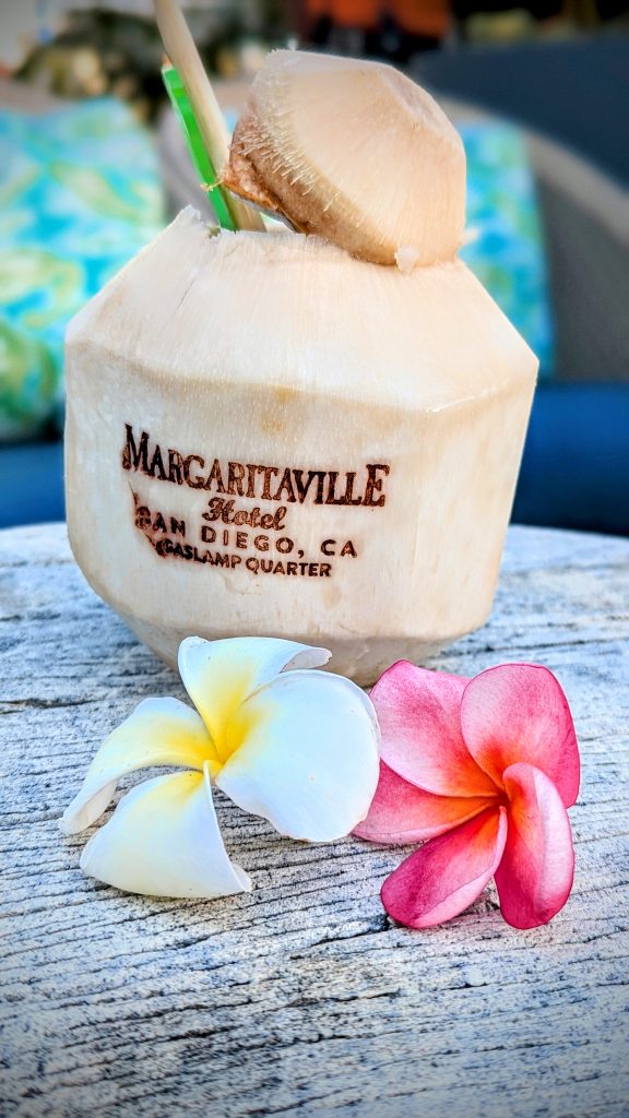 coconut with  Margaritaville Hotel San Diego text carved into skin and 2 flowers