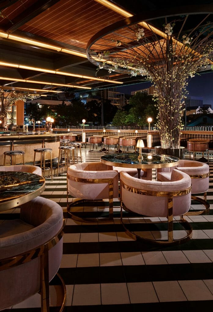 Stunning rooftop bar at Born and Raised San Diego with plush round pink chairs, black and white tile floor, 