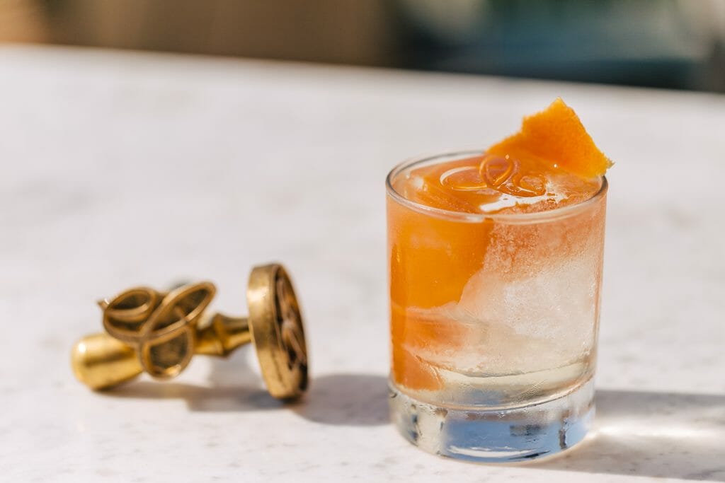 Clear drink with an orange peel on the right, golden cuffling on the right