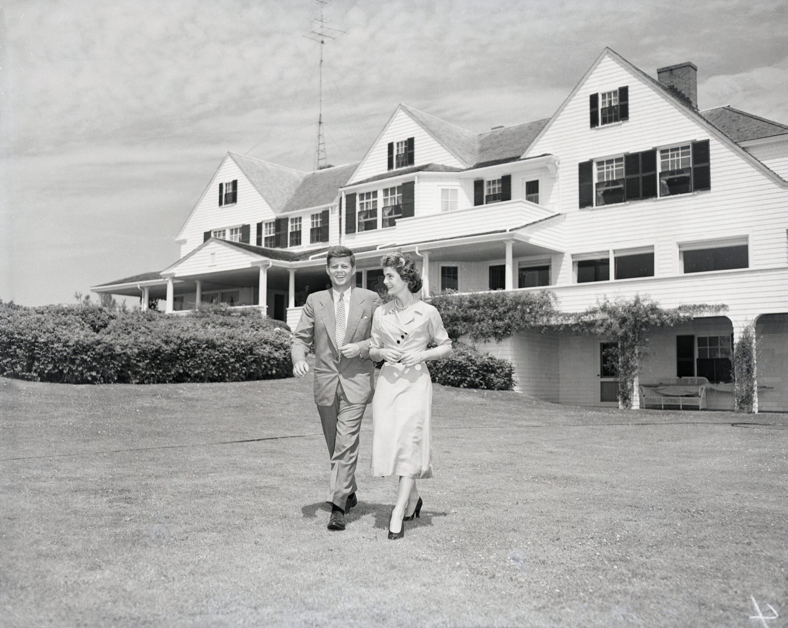 Senator John F. Kennedy and Miss Jacqueline Bouvier stroll across the lawn of his family's home after announcing their engagement.