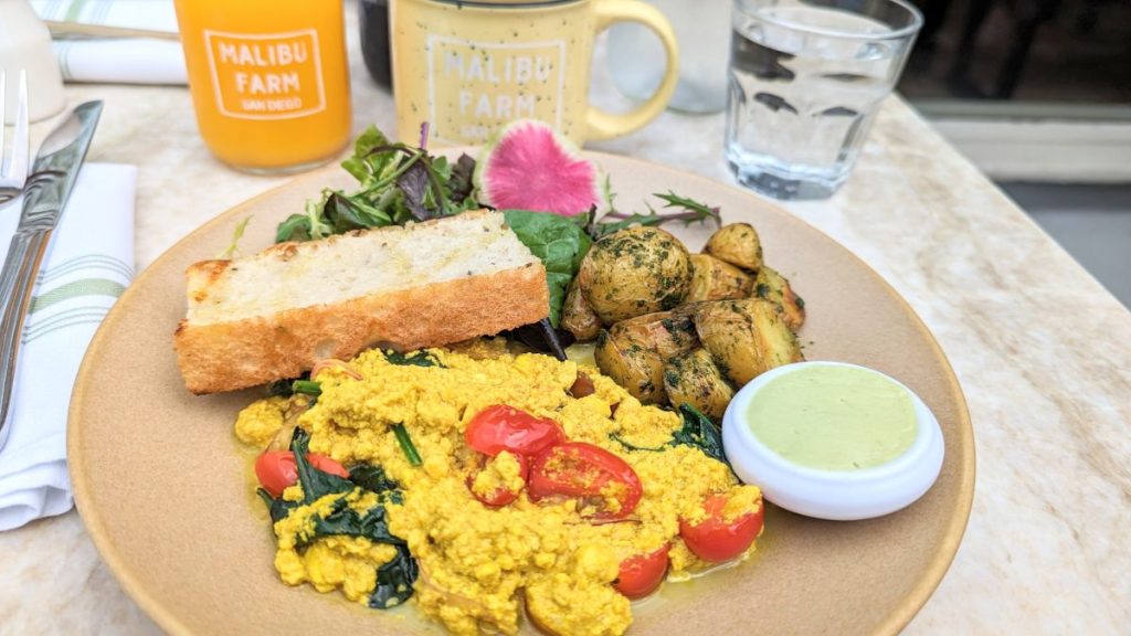 Tofu Scramble with potatoes and side salad and a piece of foccaccia with basil butter Malibu Farms Seaport Village