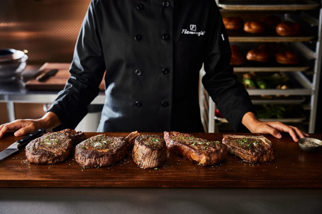 Chef with steaks from San Diego steakhouse Fleming’s Prime Steakhouse & Wine Bar