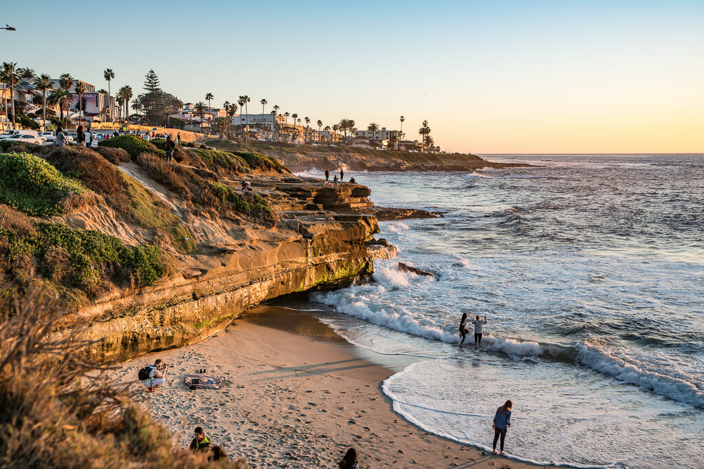 Orange sandstone cliffs in La Jolla with small beach during sunset