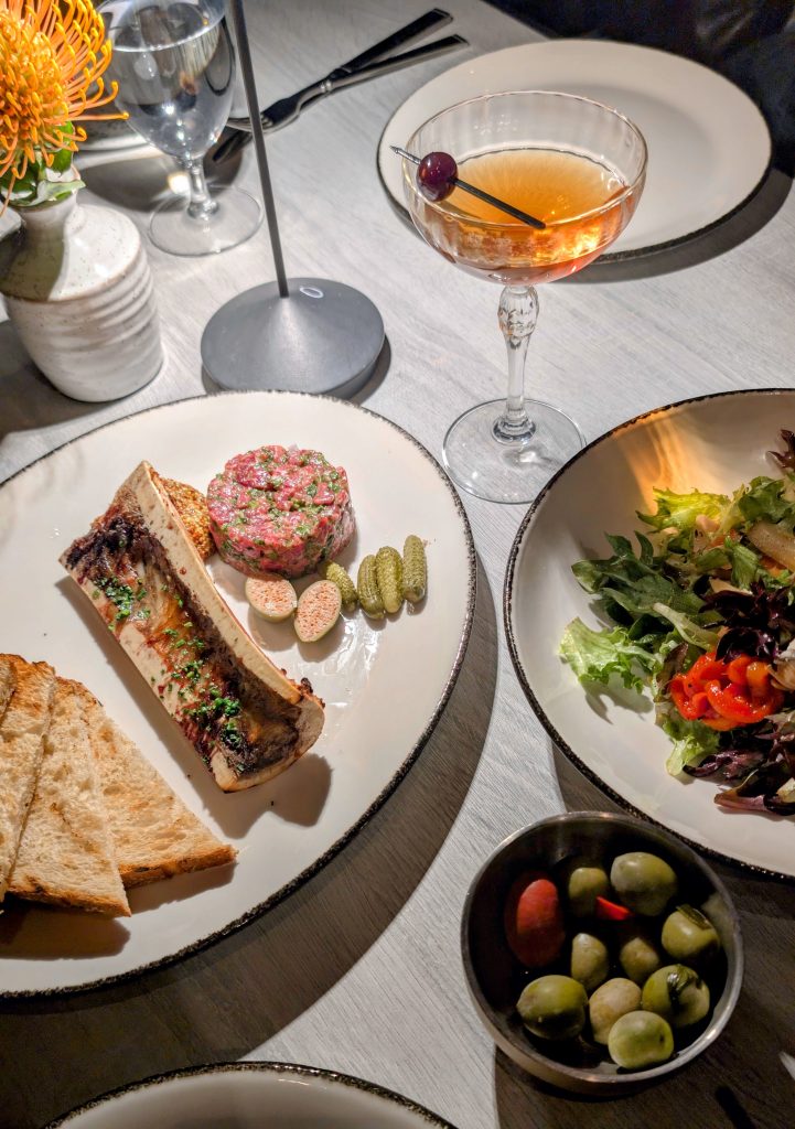 Salad, olives, tartare with bone marrow on table at The Victor Santa Ynez