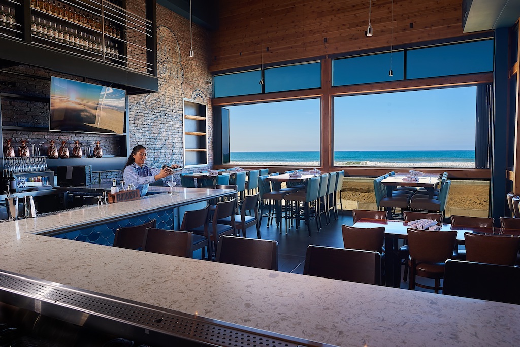 A gorgeous view of the beach out the window of a modern bar