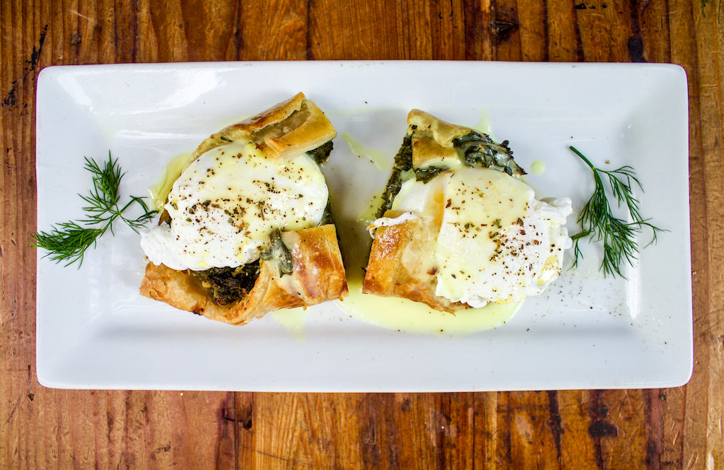 Eggs benedict with spanakopita on top under the poached eggs