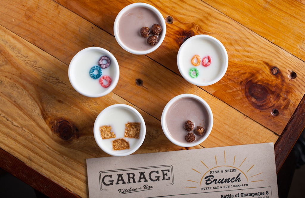 Five shot glasses filled with liquor and different cereals arranged in a pentagon