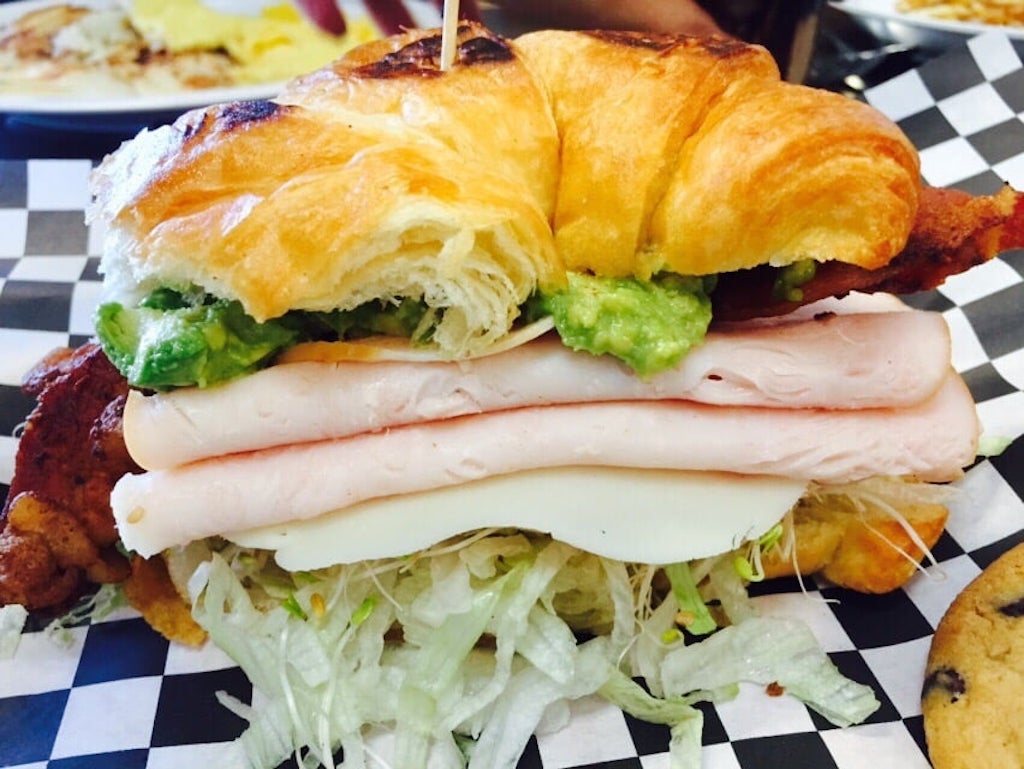 A croissant sandwich loaded with meat, cheese, and veggies