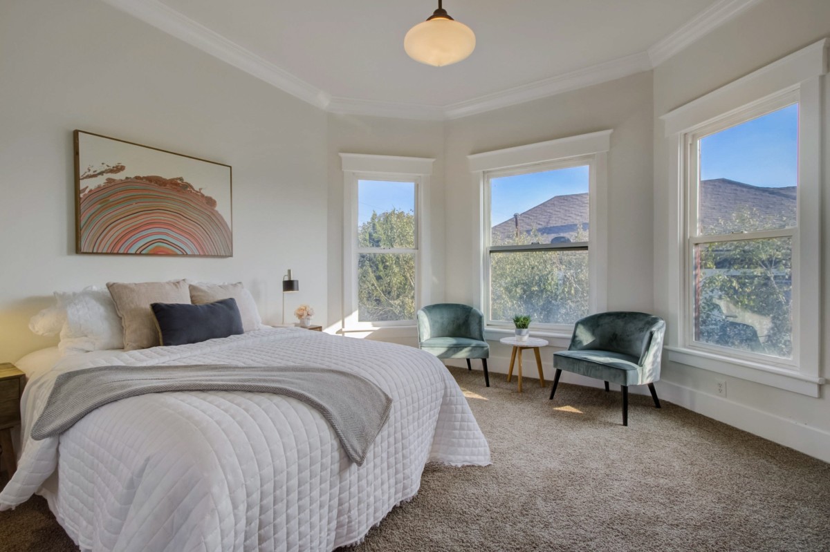 simple staged bedroom with light decor and paintings